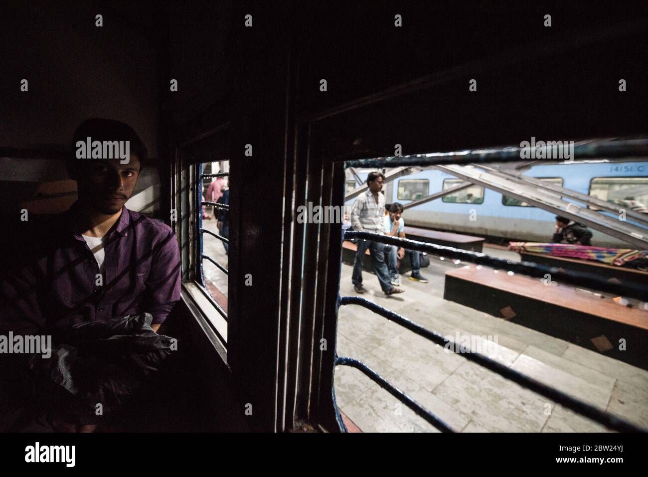 Hombre mirando por la ventana de un tren de segunda clase en movimiento. Ferrocarriles indios. India. Foto de stock