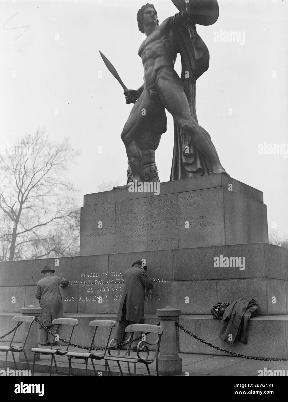 La estatua de Aquiles se está limpiando por primera vez en años. Por primera vez en diez años se está limpiando la estatua de Aquiles erigida en memoria del duque de Wellington en Hyde Park, Londres, y se está reconstruyendo la inscripción. Obreros que regilaban las letras de la estatua. 24 Febrero 1932 30s, 30s, 30s, 30s, 30s, 30s, 1930s Foto de stock