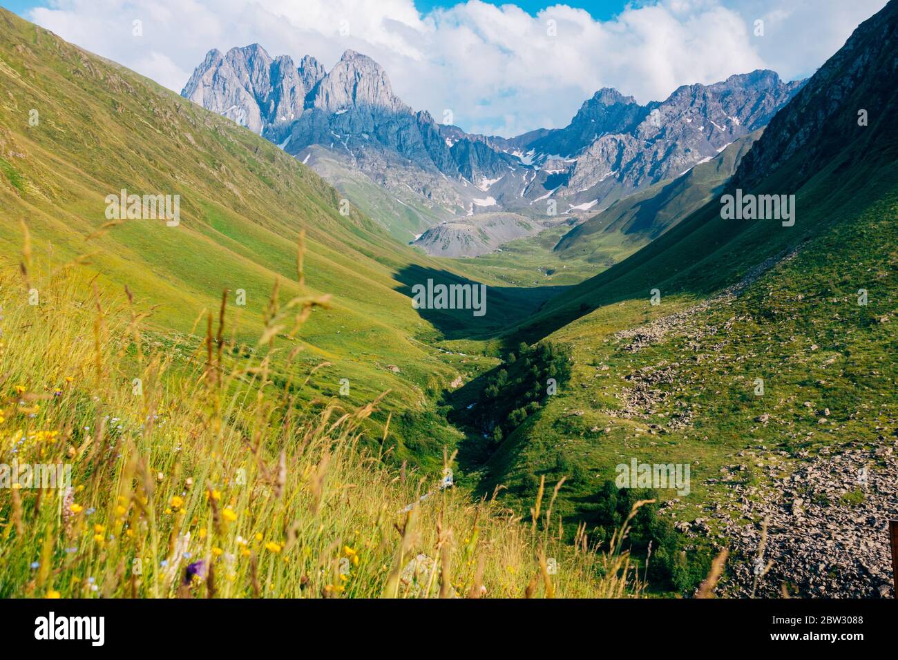 El pico de la montaña de Chaukhi y el río de Chaukhistskali, visto desde el valle abajo en un día caluroso de verano en Georgia Foto de stock