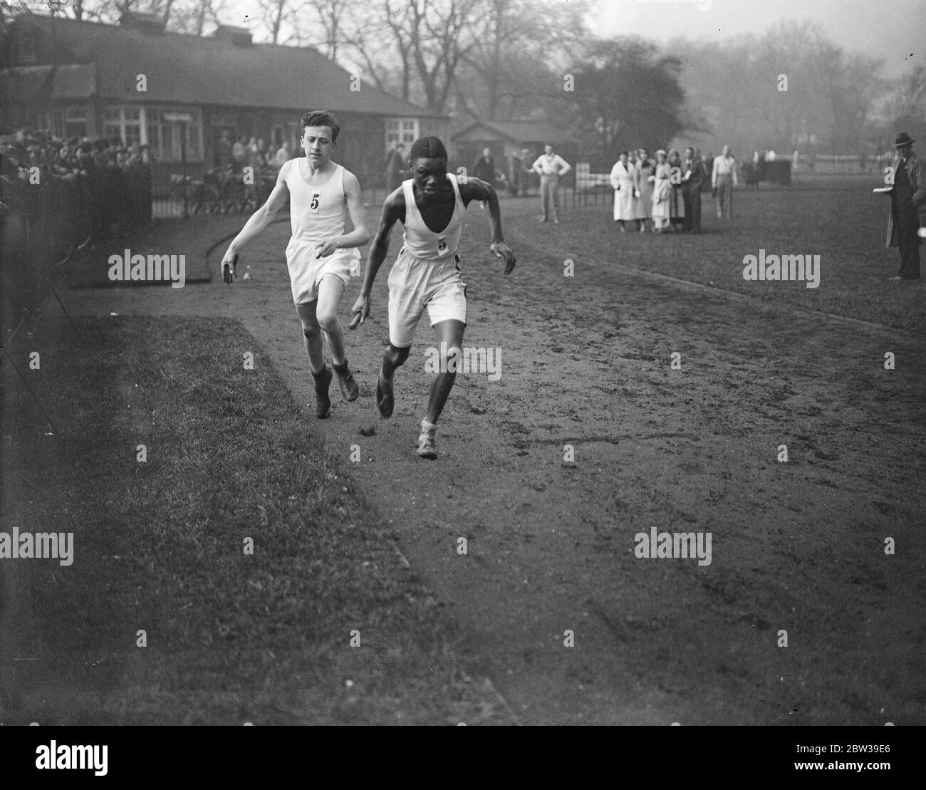 Corredores en una carrera de relés . El atleta negro se hace cargo del batuta. Abril 1934 Foto de stock