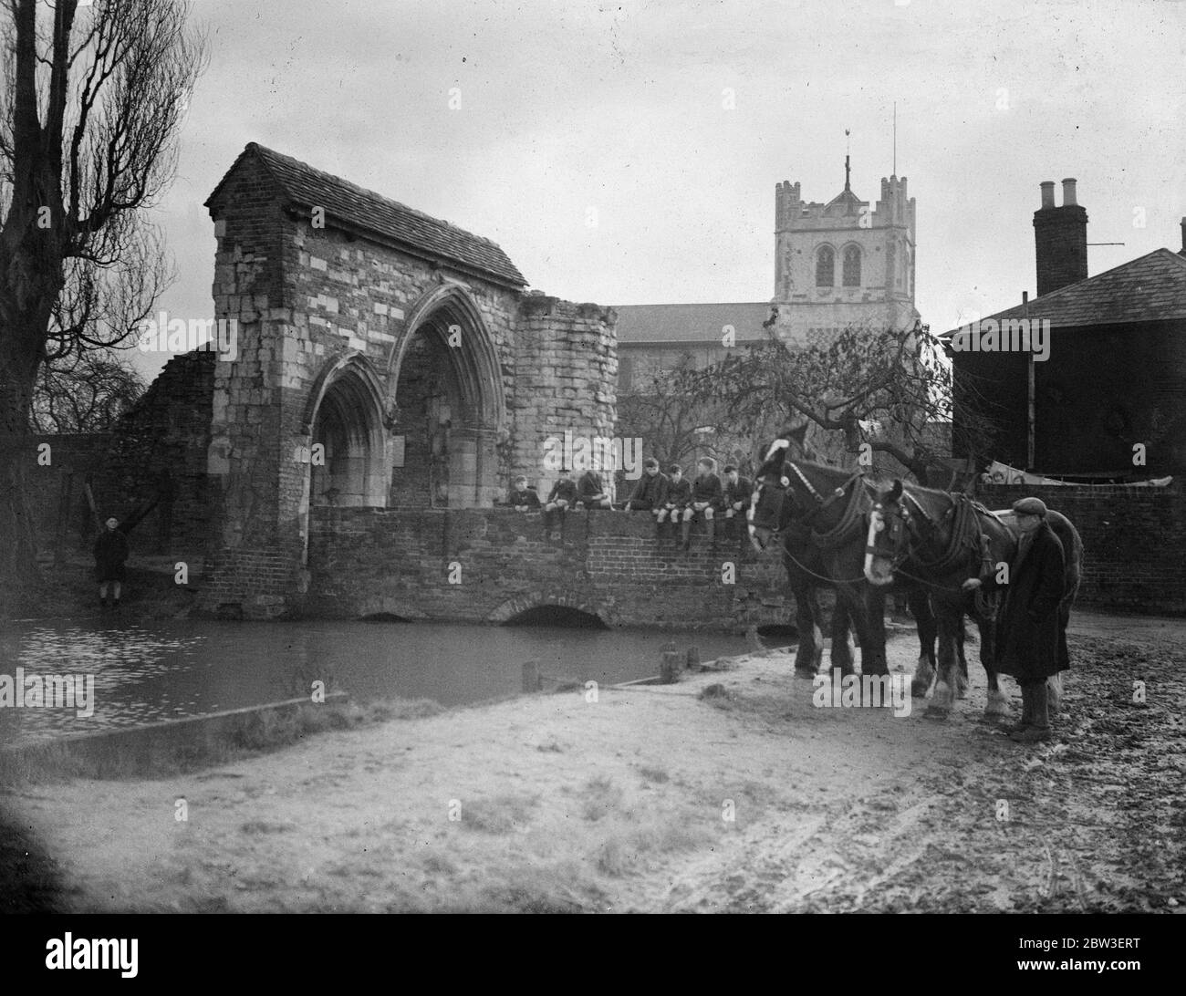 Remanente de un pasado glorioso. Un equipo de caballos de granja por la antigua puerta de entrada a la Abadía de Waltham y la iglesia de la Abadía , que tiene 875 años de edad. 15 de enero de 1935 Foto de stock