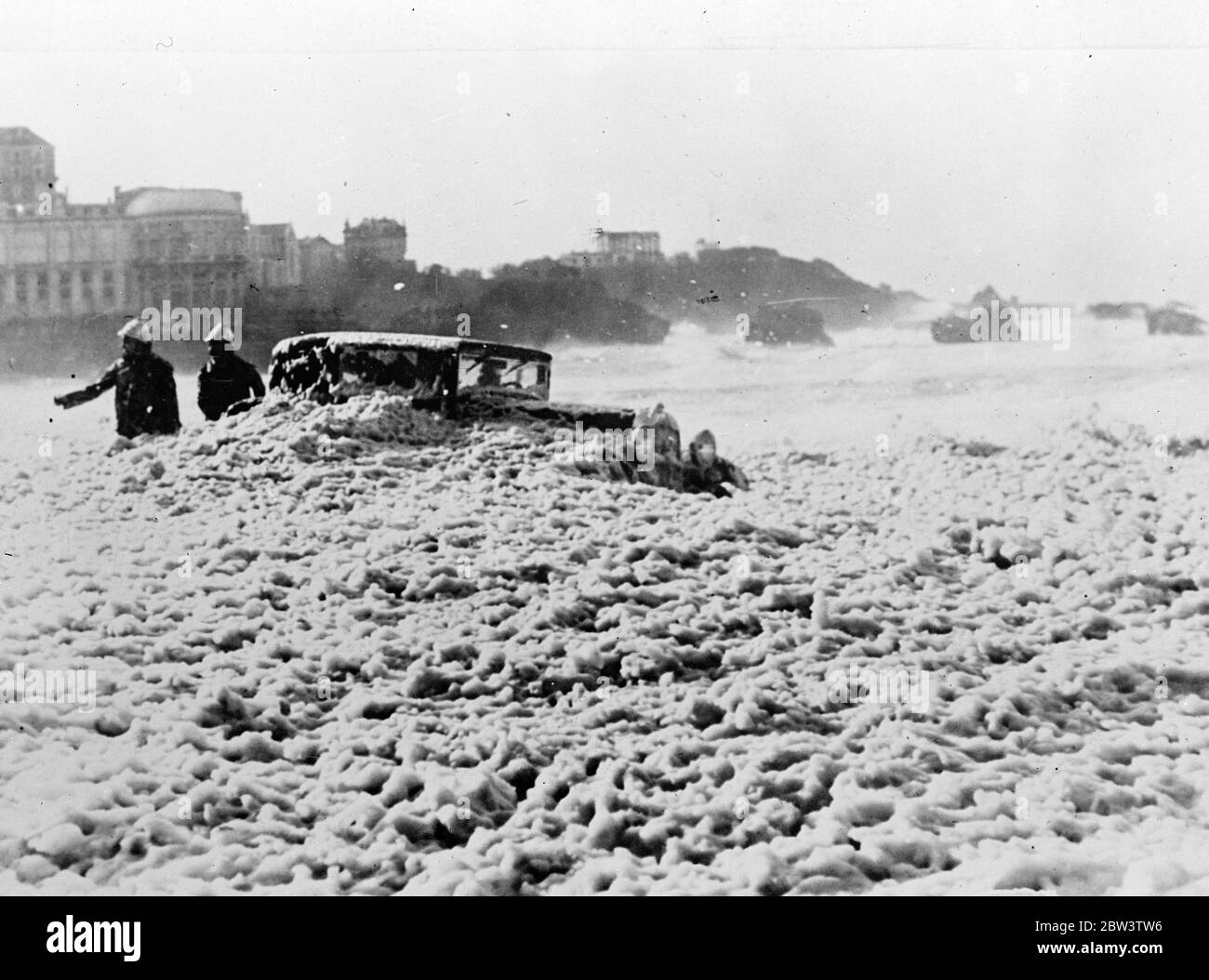 Como un mar de jaboneras. Taxis atrapados por el monstruo de la tormenta en Biarritz. Bomberos tratando de liberar un coche de la espuma en la que casi ha desaparecido en Biarritz. 7 de diciembre de 1935 Foto de stock