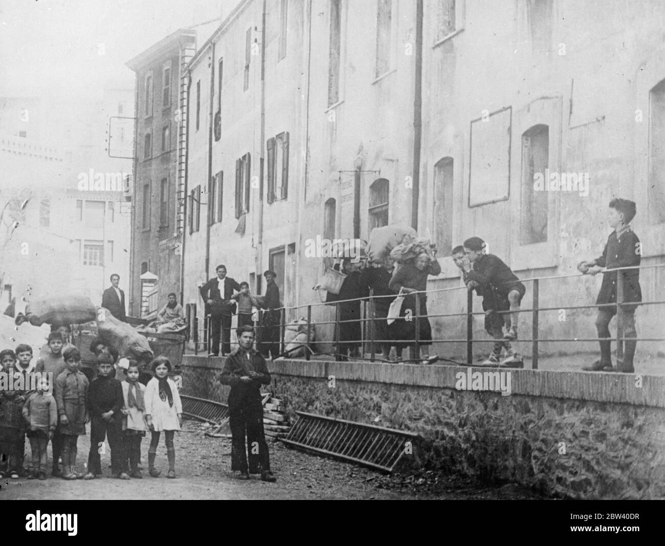 Soportar la carga de la Guerra Civil. Sacos de alimentos para los refugiados. Se están distribuyendo provisiones entre cientos de refugiados españoles en la ciudad de Corbere, Francia - frontera española, donde la situación de muchas personas mayores es lamentable. Después de la distribución de alimentos, las personas mayores pueden verse inclinadas bajo sacos pesados mientras se fueron a los hogares temporales. Fotos: Mujeres ancianas refugiadas llevando sacos de pan después de haber sido distribuidos de un carro en Corbere. 7 de abril de 1937 Foto de stock