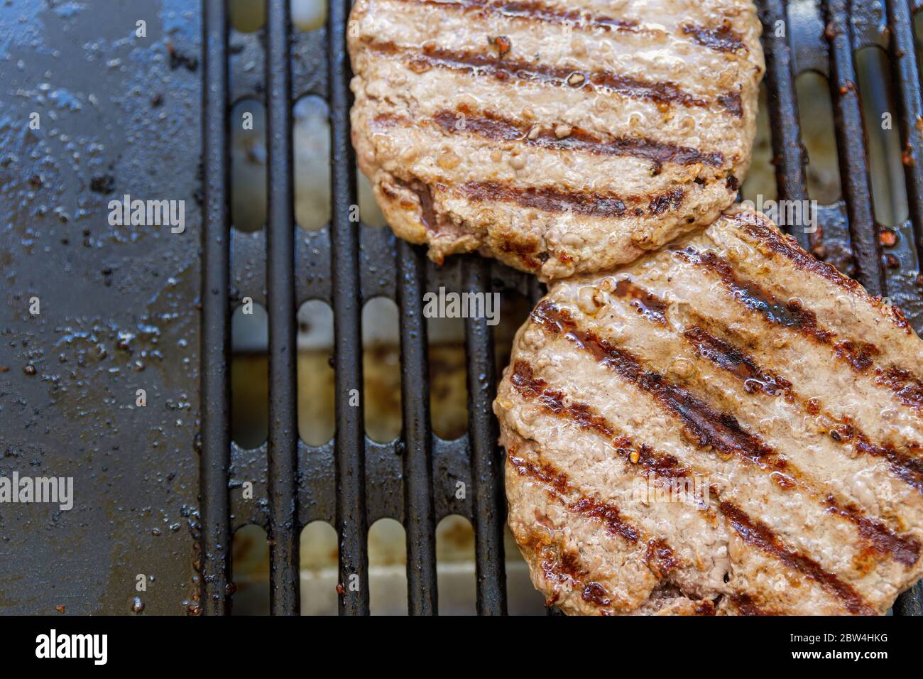 Dos grandes patios de hamburguesas de carne bio a la parrilla en una parrilla  eléctrica. Concepto de comida de manía grasosa y poco saludable Fotografía  de stock - Alamy