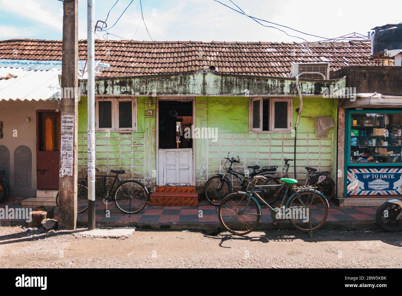 Bicicletas estacionadas frente a una pequeña casa en una calle en Kochi, India Foto de stock