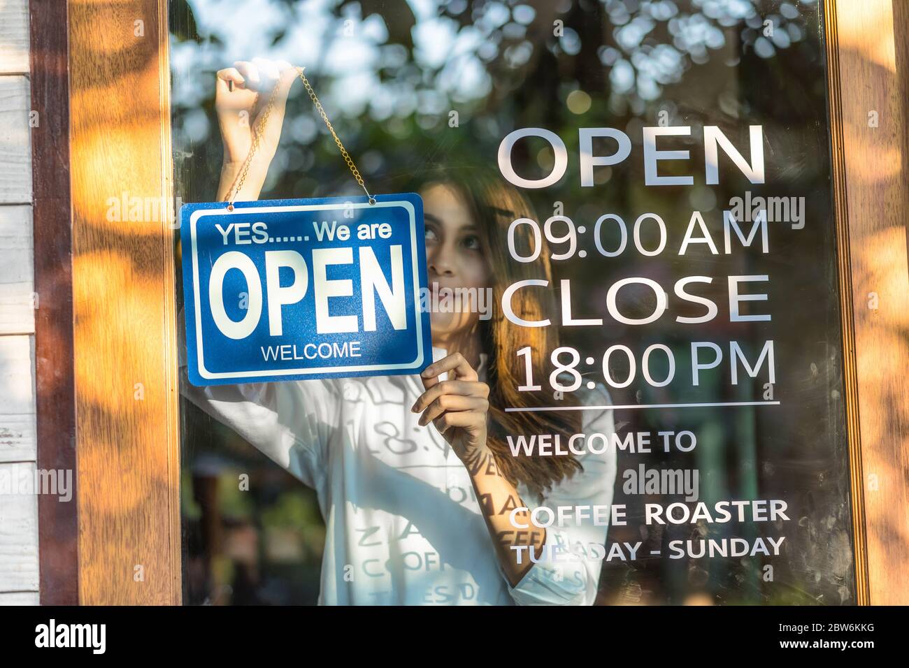Closeup asiática joven asia que fija signo abierto en la tienda gafas para  dar la bienvenida al cliente en la cafetería, el propietario de la pequeña  empresa y la puesta en marcha