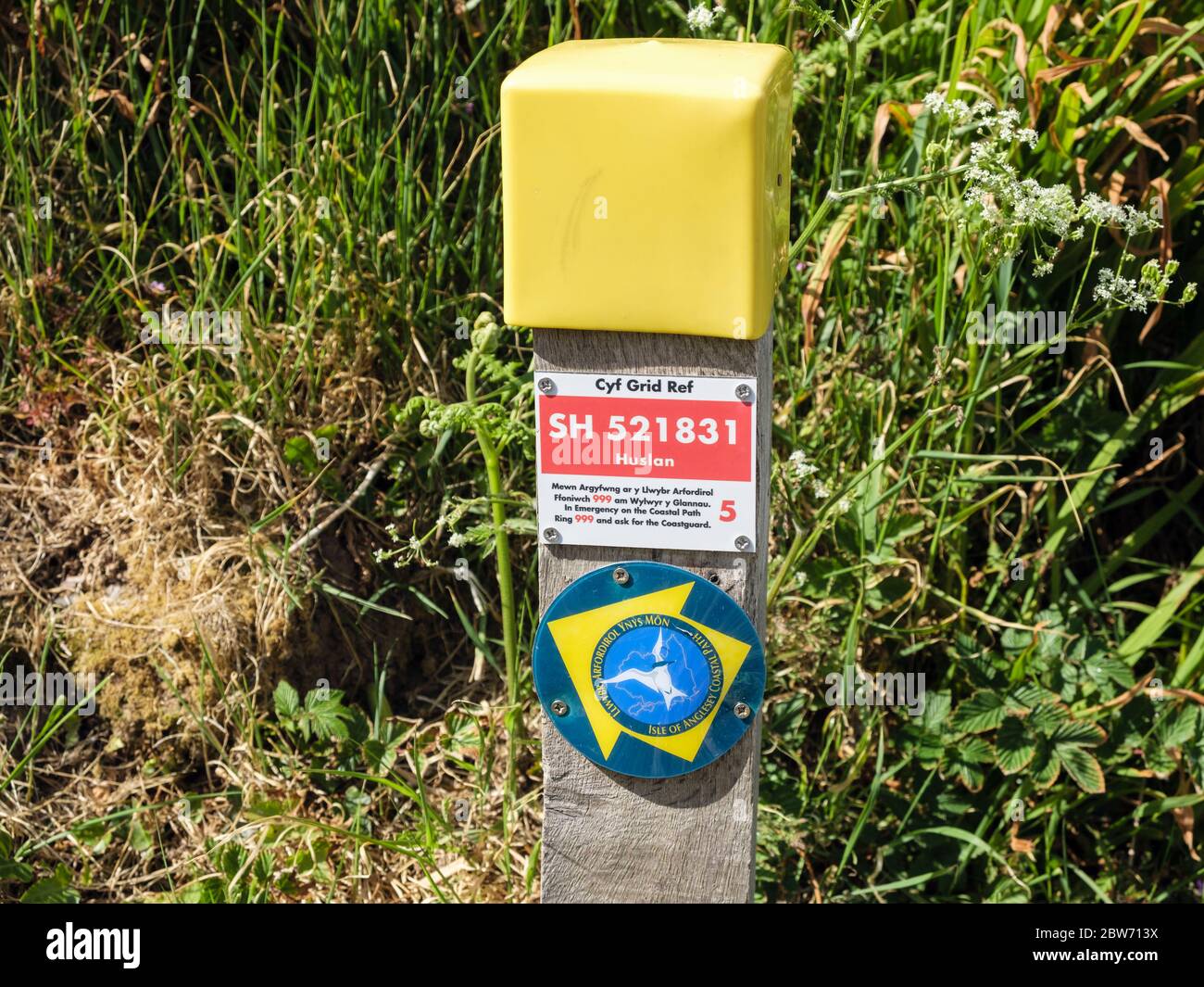 Referencia de cuadrícula roja bilingüe de guardacostas en el camino costero de Gales señal de dirección marcador de camino puesto. Benllech, Isla de Anglesey, Gales, Reino Unido, Gran Bretaña Foto de stock