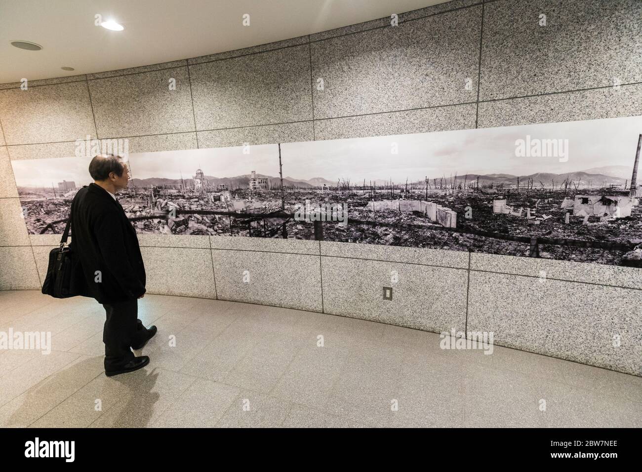 Hombre mirando la imagen de una ciudad bombardeada, dentro del Salón Nacional de la Paz de Hiroshima, Japón Foto de stock