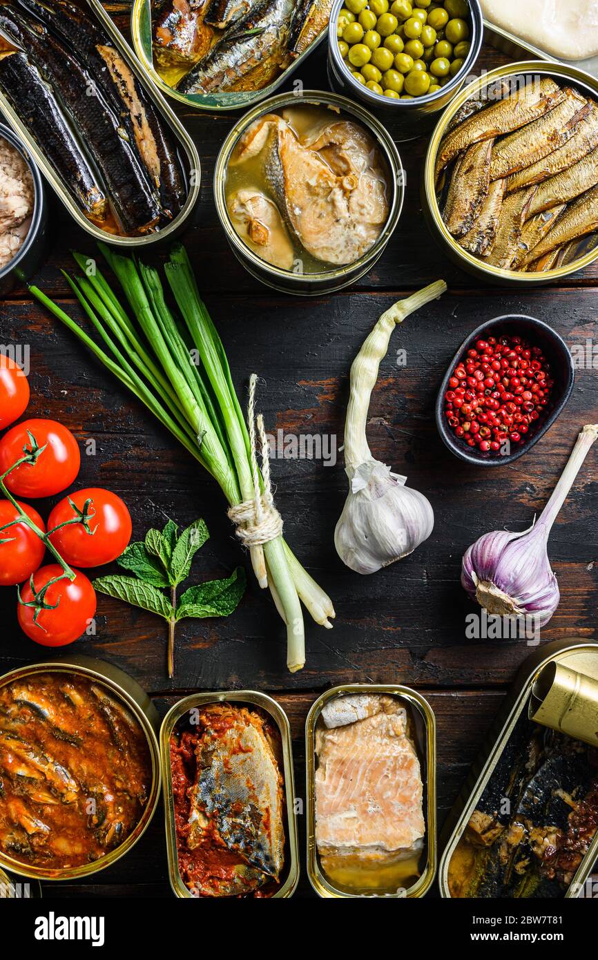 Conserva los alimentos enlatados en latas con ingredientes biológicos frescos tomatoe hierbas vegetales preparados con limón, carne, pescado y frutas en latas de lata en el viejo Foto de stock