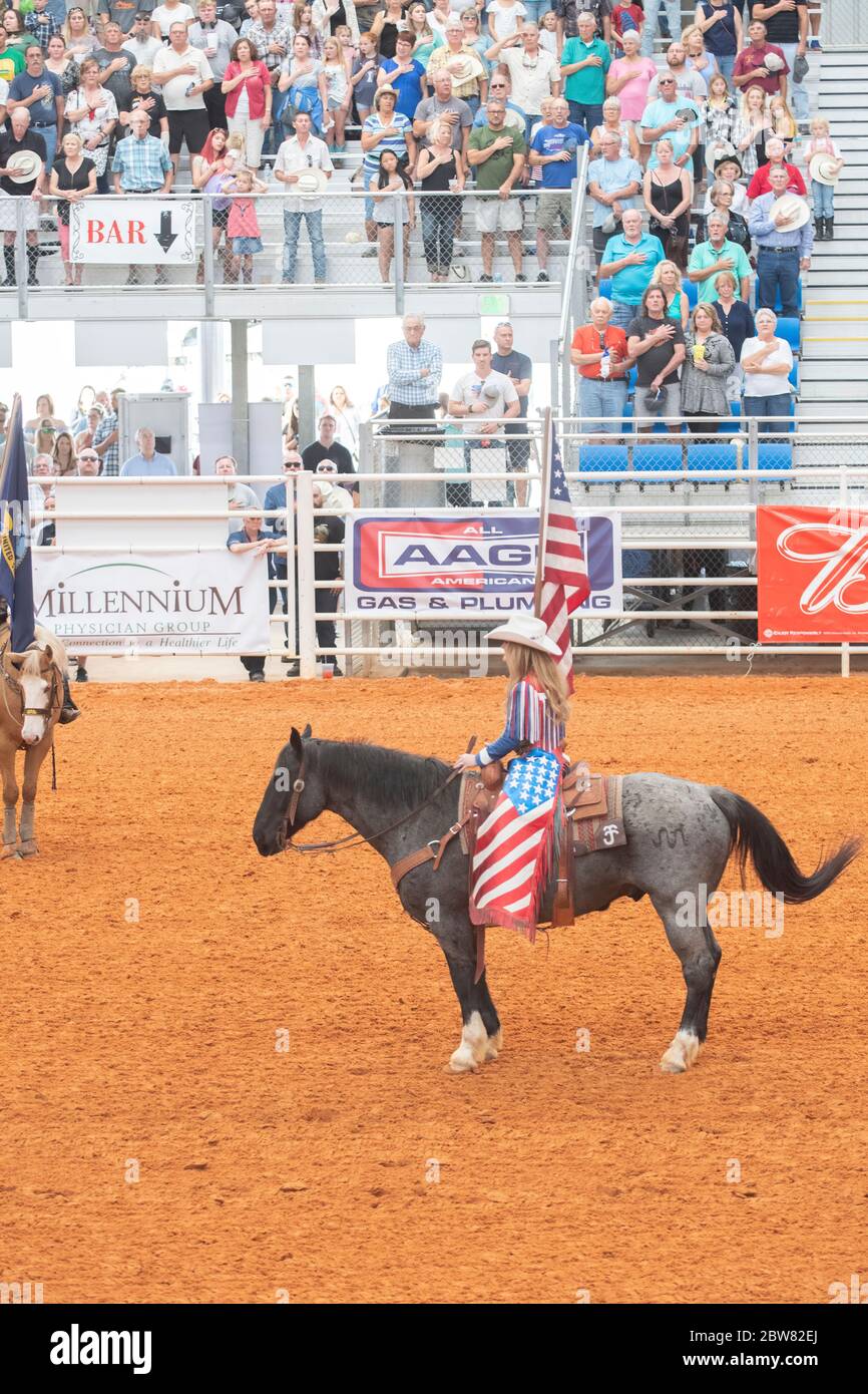 Un joven joven tiene una bandera americana durante las ceremonias de apertura en el rodeo del Campeonato de Arcadia All-Florida Foto de stock