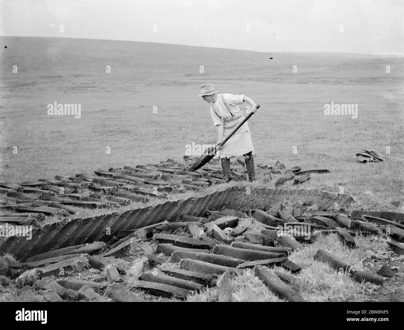 Una mano de granja corta bloques de turba en Warleggan, Bodmin . 1936 . Foto de stock