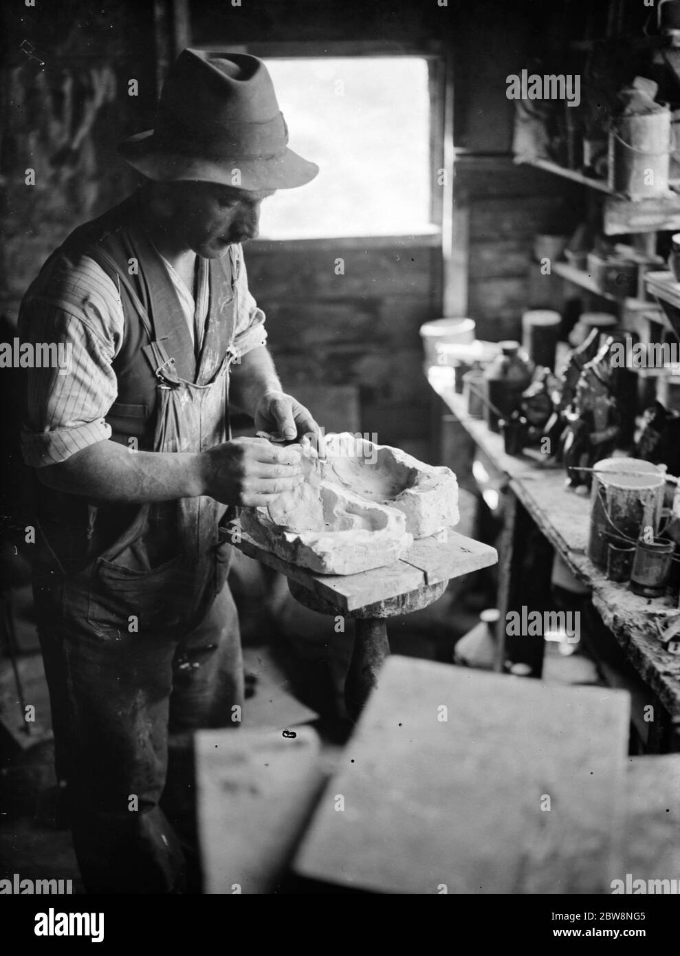 El Sr. Sadler, fabricante de alfarería, llenando los lados de un molde de conejo con arcilla. 1938 Foto de stock