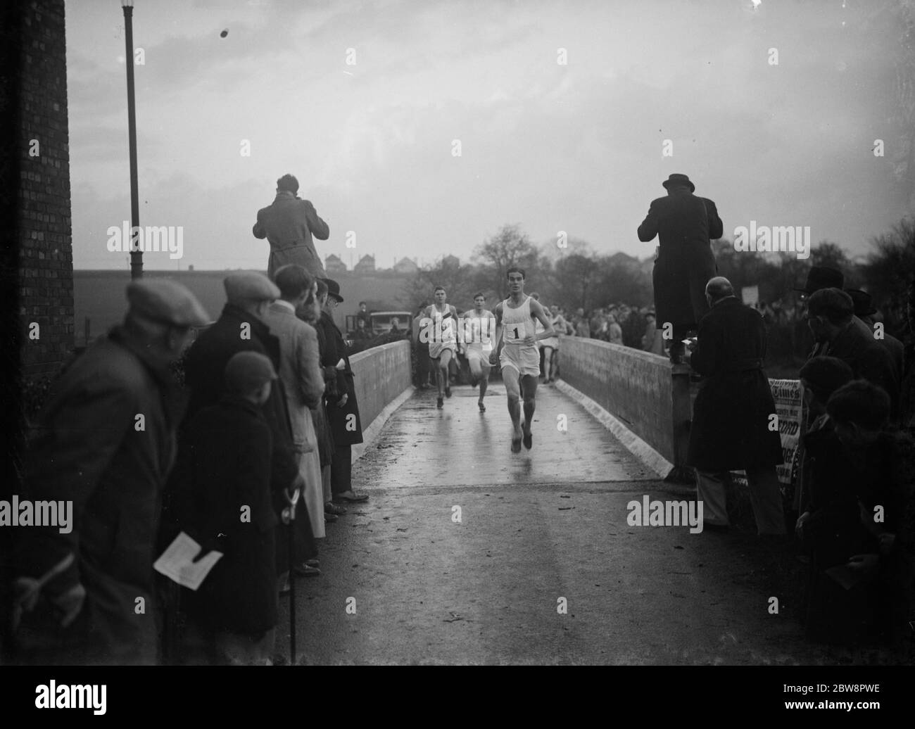 Corredores que cruzan el puente durante la carrera de campo a través de la Universidad de Oxford contra la Universidad de Cambridge en Horton Kirby, Kent . 1937 Foto de stock