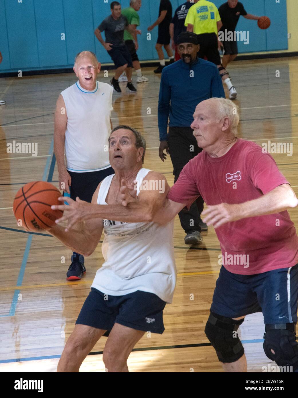 Los jugadores de baloncesto senior interbloquean los brazos mientras juegan en un centro de recreación en Englewood, Florida, EE.UU. Foto de stock