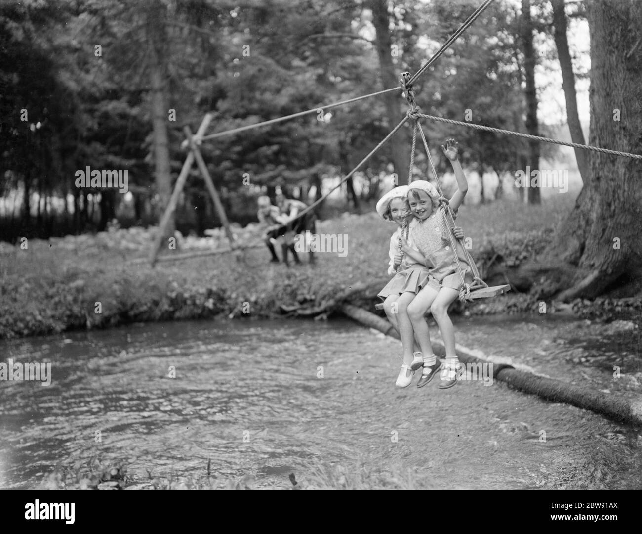 Scouts usando una silla de un jovencito para tirar de dos niñas pequeñas a través de un arroyo. 19 de junio de 1939 Foto de stock