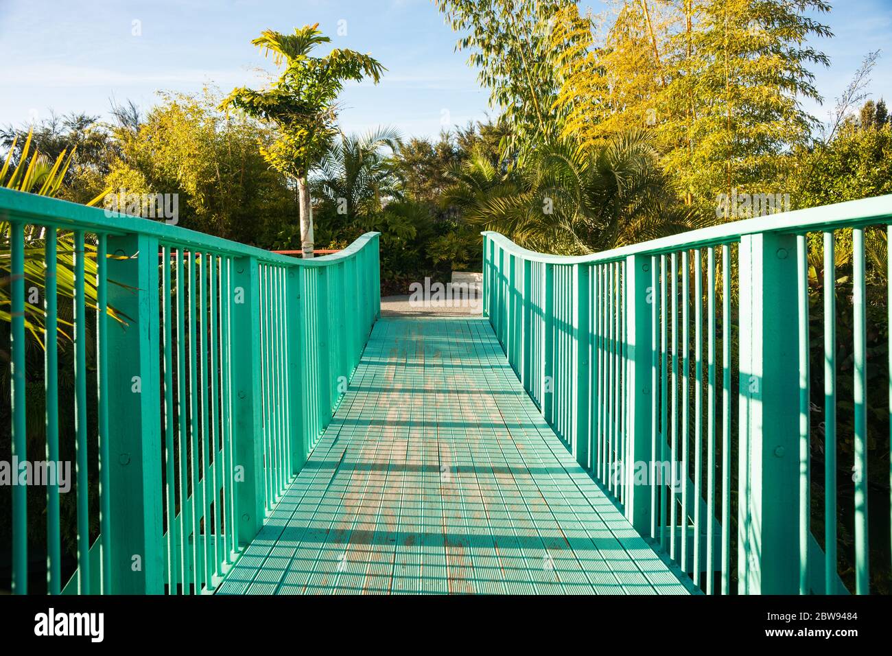 Líneas de guía de la barandilla azul puente peatonal y camino que cruza el valle a los jardines paisajistas. Foto de stock