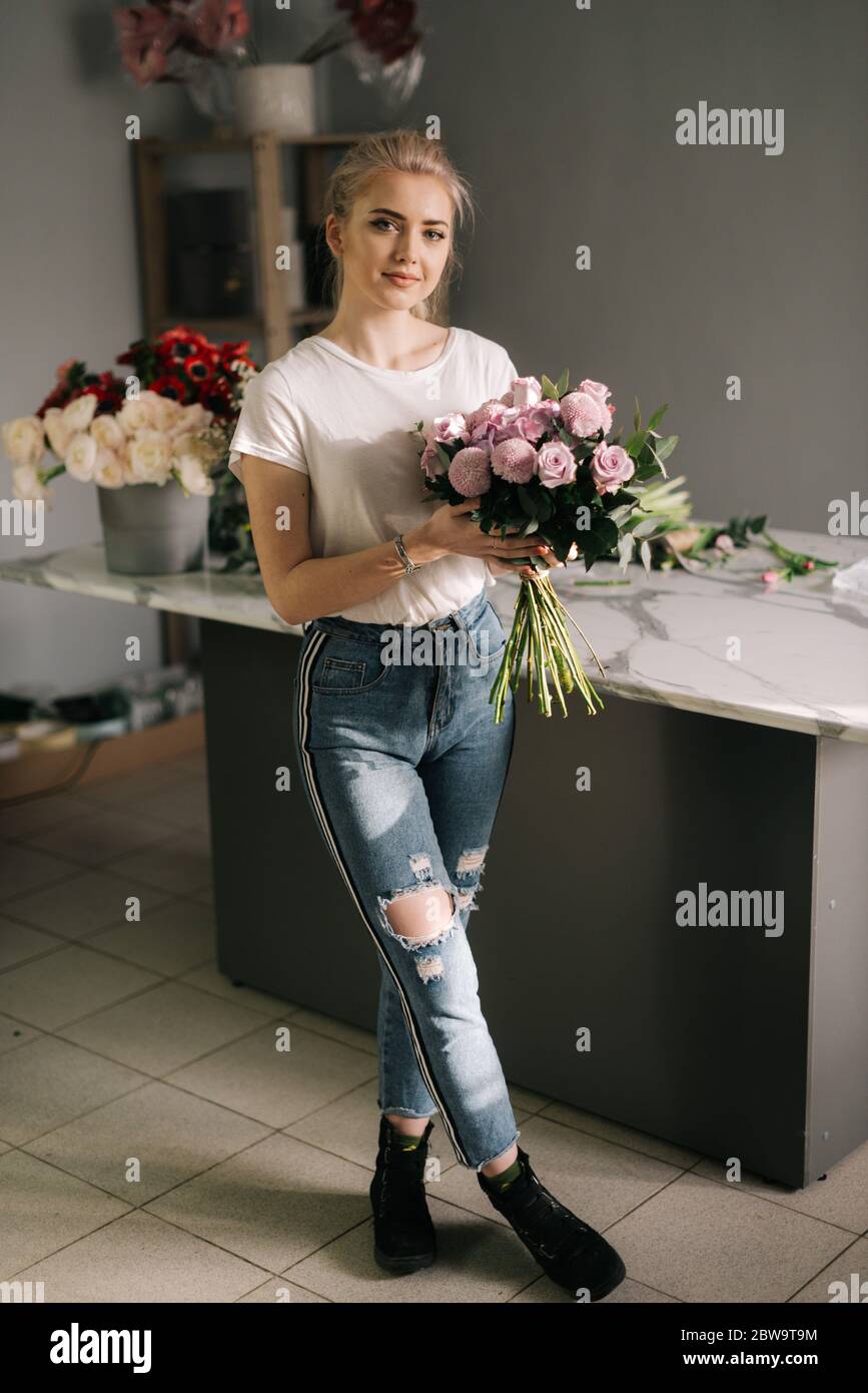 Mujer joven bonita con ropa de moda que sostiene ramo de flores Fotografía  de stock - Alamy