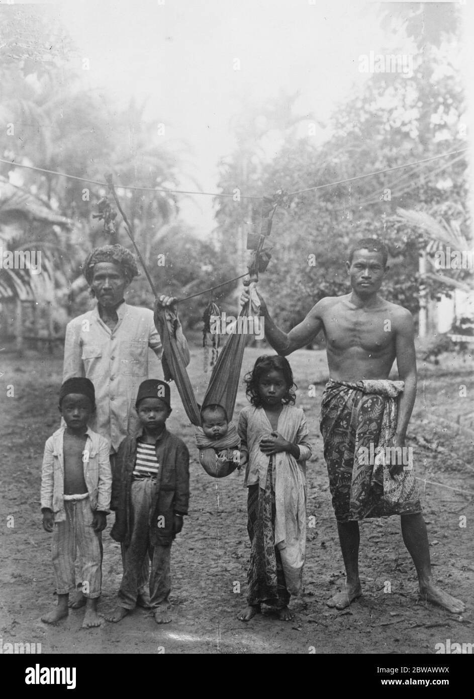 Expedición de Frederick Burlingham en Borneo Central Cómo los hombres salvajes de Borneo protegen a sus jóvenes de los reptiles en lugar de cunas, los niños son engullados para que no puedan caer y se cuelgan como se muestra en una vid de ratán estirada de un árbol a otro 21 de octubre de 1921 Foto de stock