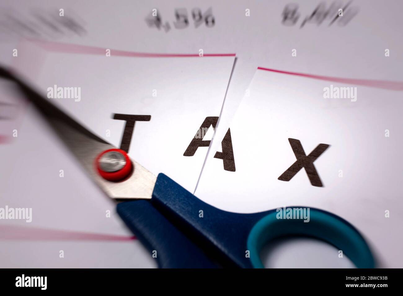 Concepto de reducción de impuestos. Sciccors cortar papel con la palabra impuesto - efecto de zoom Foto de stock