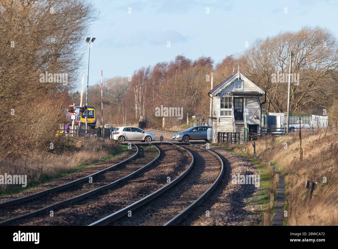 Network Rail y los coches que cruzan el nivel de cruce en Elsham, Lincolnshire, Reino Unido con un tren. Foto de stock