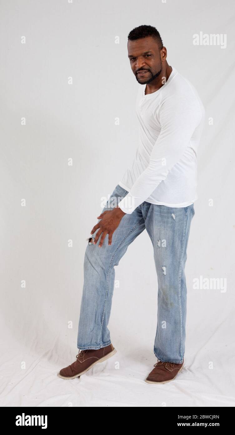 Hombre negro pensativo en camisa blanca y jeans Fotografía de stock - Alamy