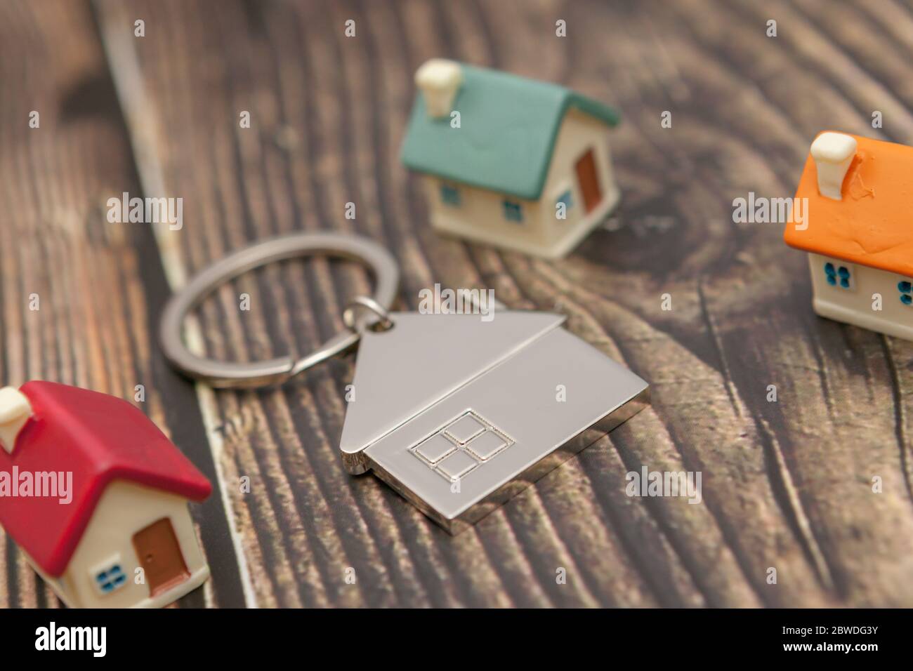 Primer plano. Varias casas de colores y una cadena de llaves sobre un fondo de madera. Foto de stock