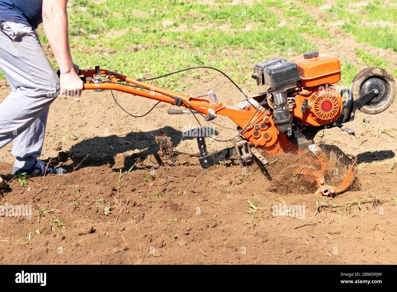 Hombre granjero arar la tierra con un cultivador. Maquinaria agrícola:  Cultivador para labranza en el jardín, cultivador de motor Fotografía de  stock - Alamy