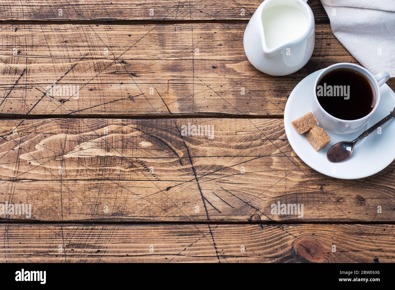 Una taza de café con aromáticos palitos de canela sobre una mesa cubierta  con granos de café.