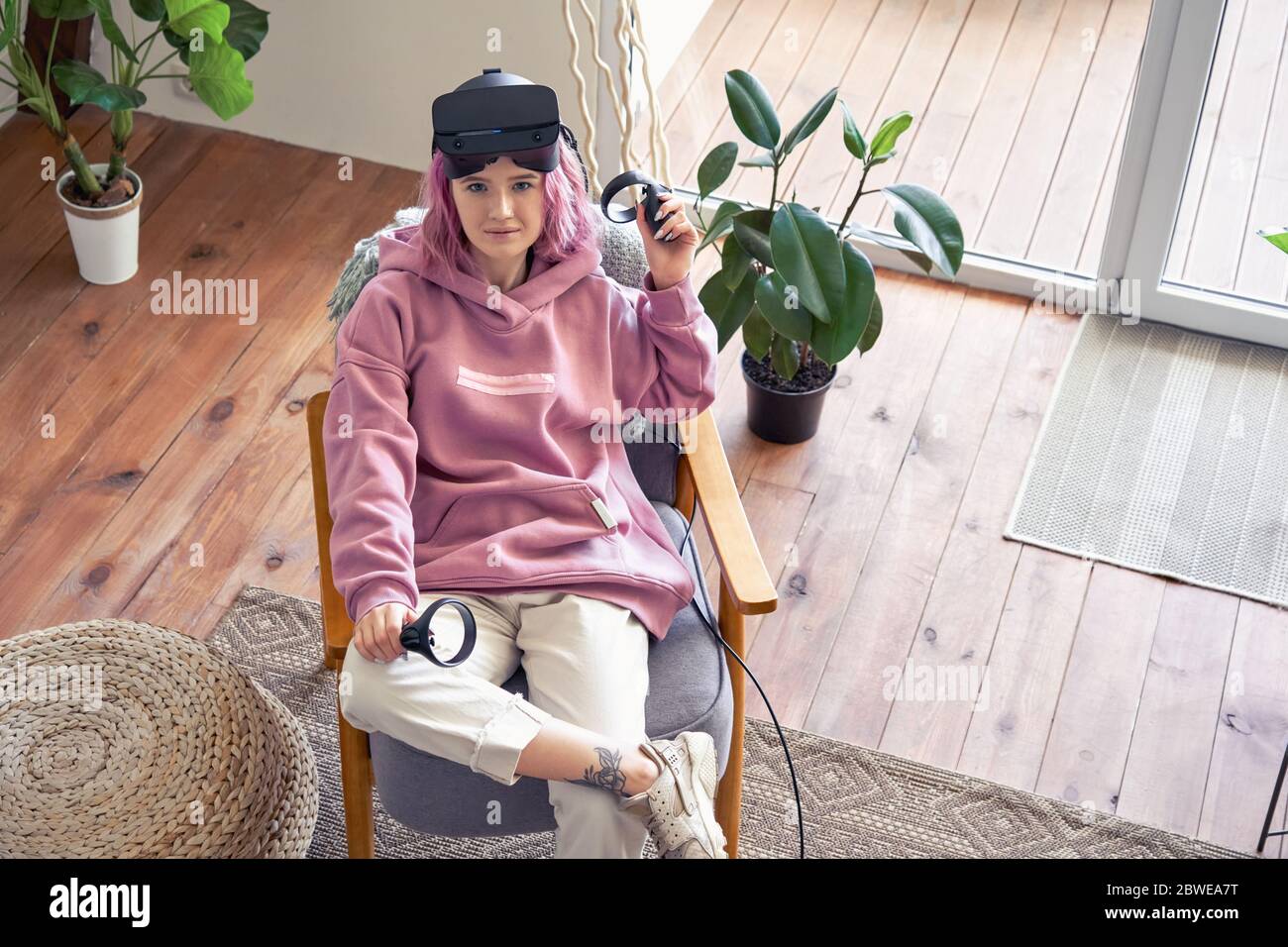 Moda adolescente niña llevar vr auricular mirar cámara sentarse en silla superior ver retrato. Foto de stock