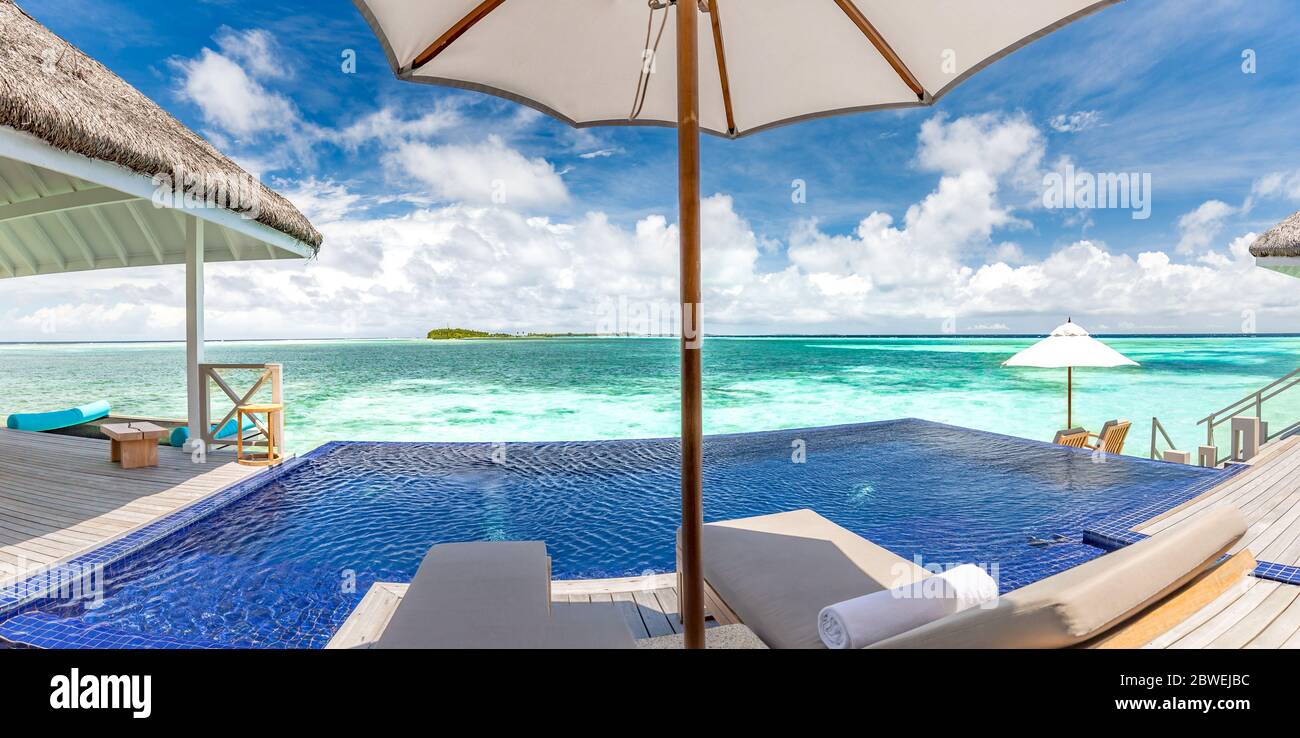 Complejo de lujo con una hermosa piscina y vistas al mar bajo el cielo azul. Lujoso paisaje de playa tropical, tumbonas y reflexión sobre el agua Foto de stock