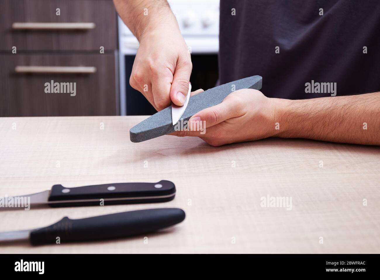 Primeros planos fuertes manos macho afilar un cuchillo de metal de cocina  con una piedra de afilar. Casa afilado de cuchillos Fotografía de stock -  Alamy