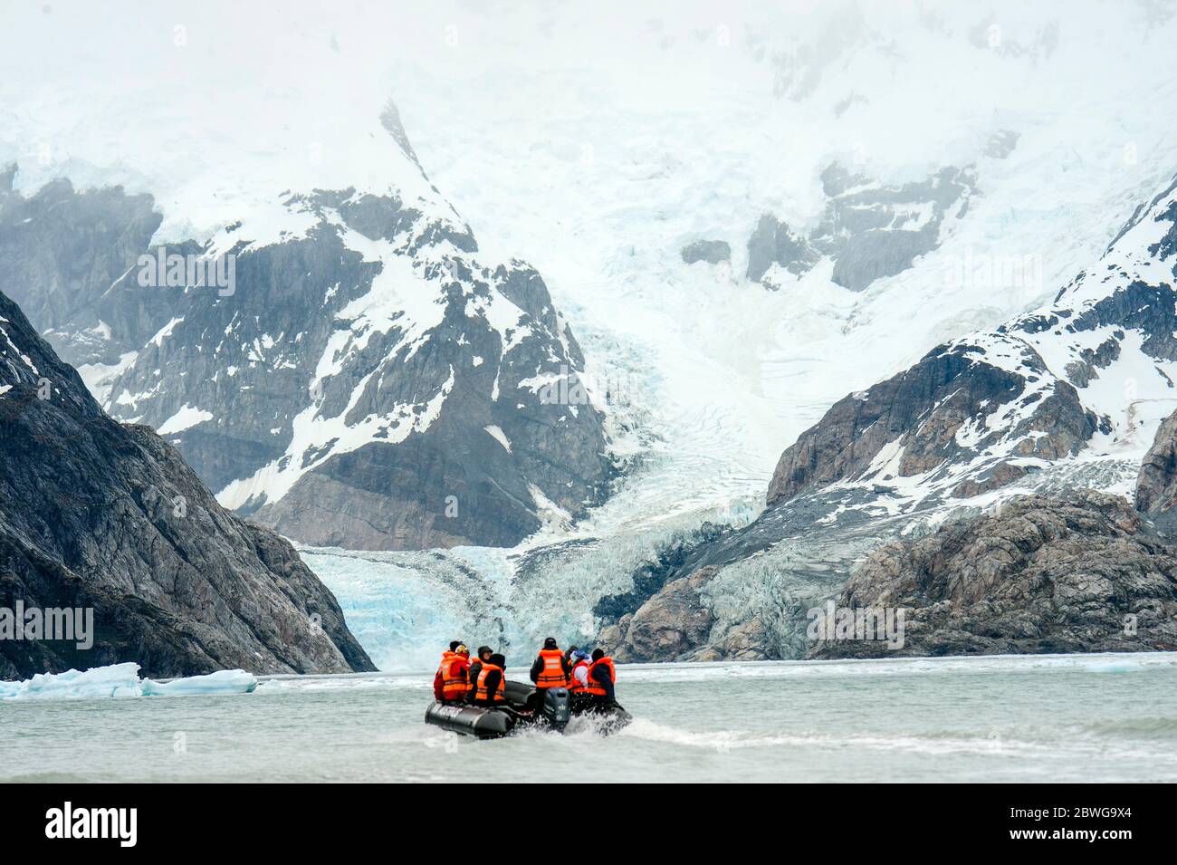 Viaje en lancha de invierno sobre río en paisaje nevado de montaña, Patagonia, Chile, América del Sur Foto de stock