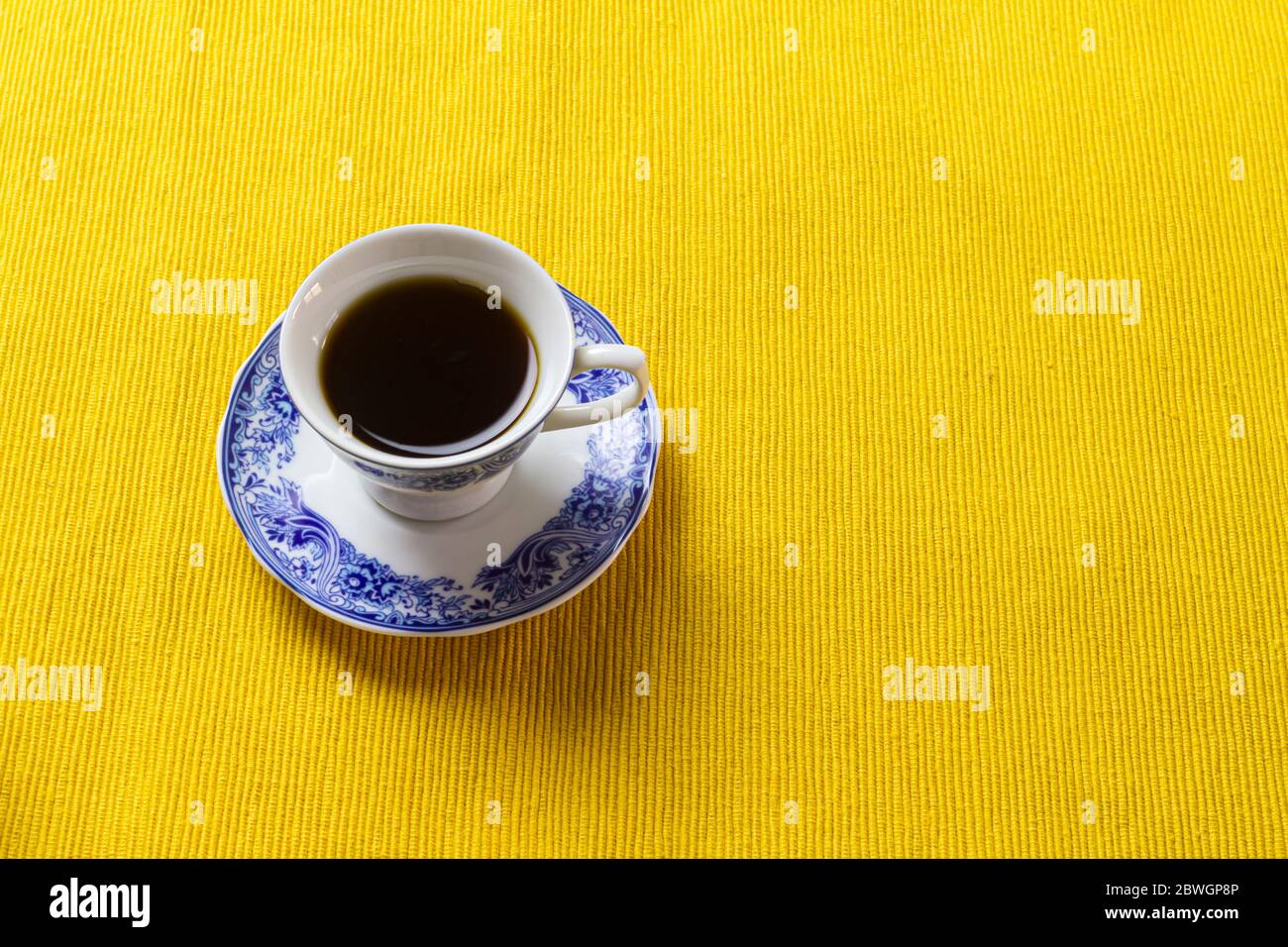 Taza de café encima de la mantel amarilla. Foto de stock