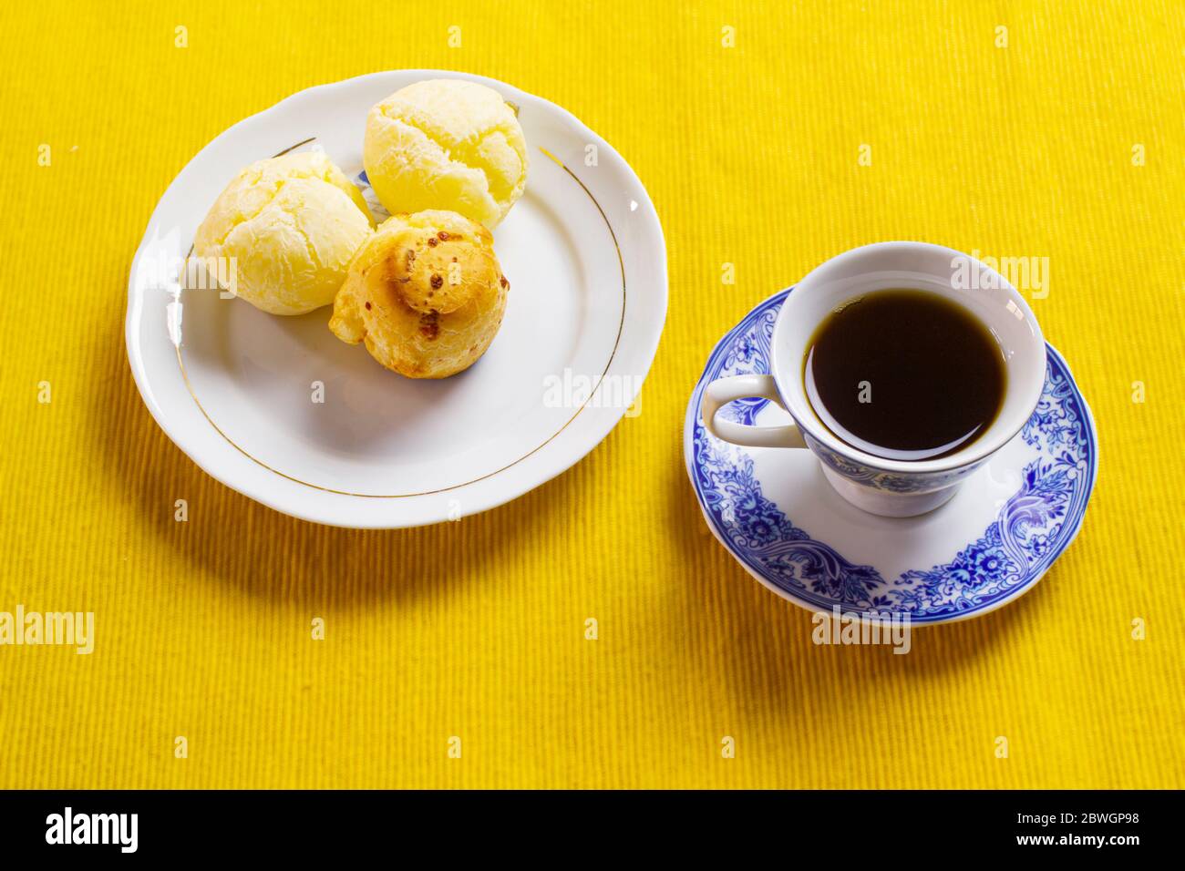 Pan de queso brasileño y taza de café y en el placemat amarillo. Foto de stock