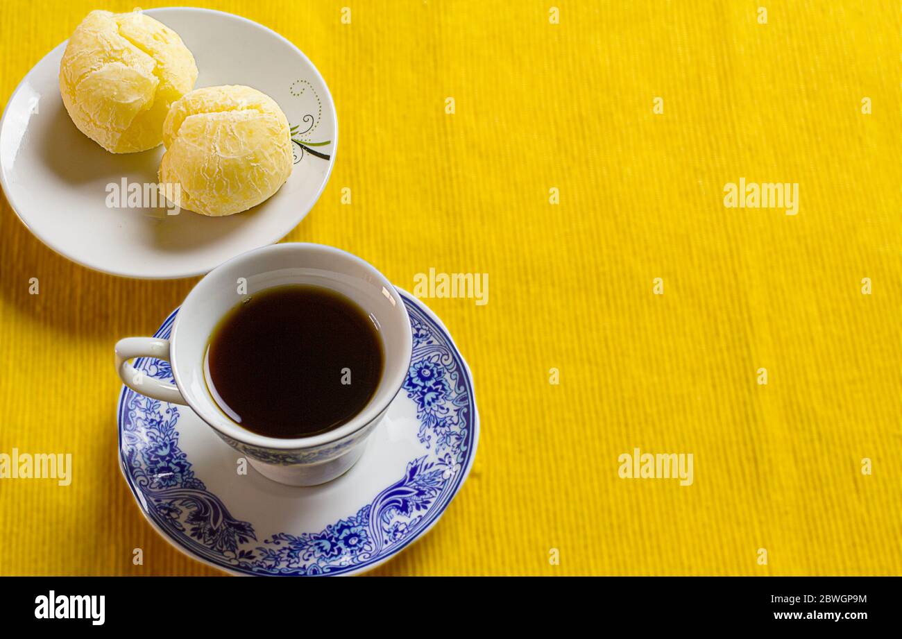 Taza de café y pan de queso brasileño en el placemat amarillo. Foto de stock