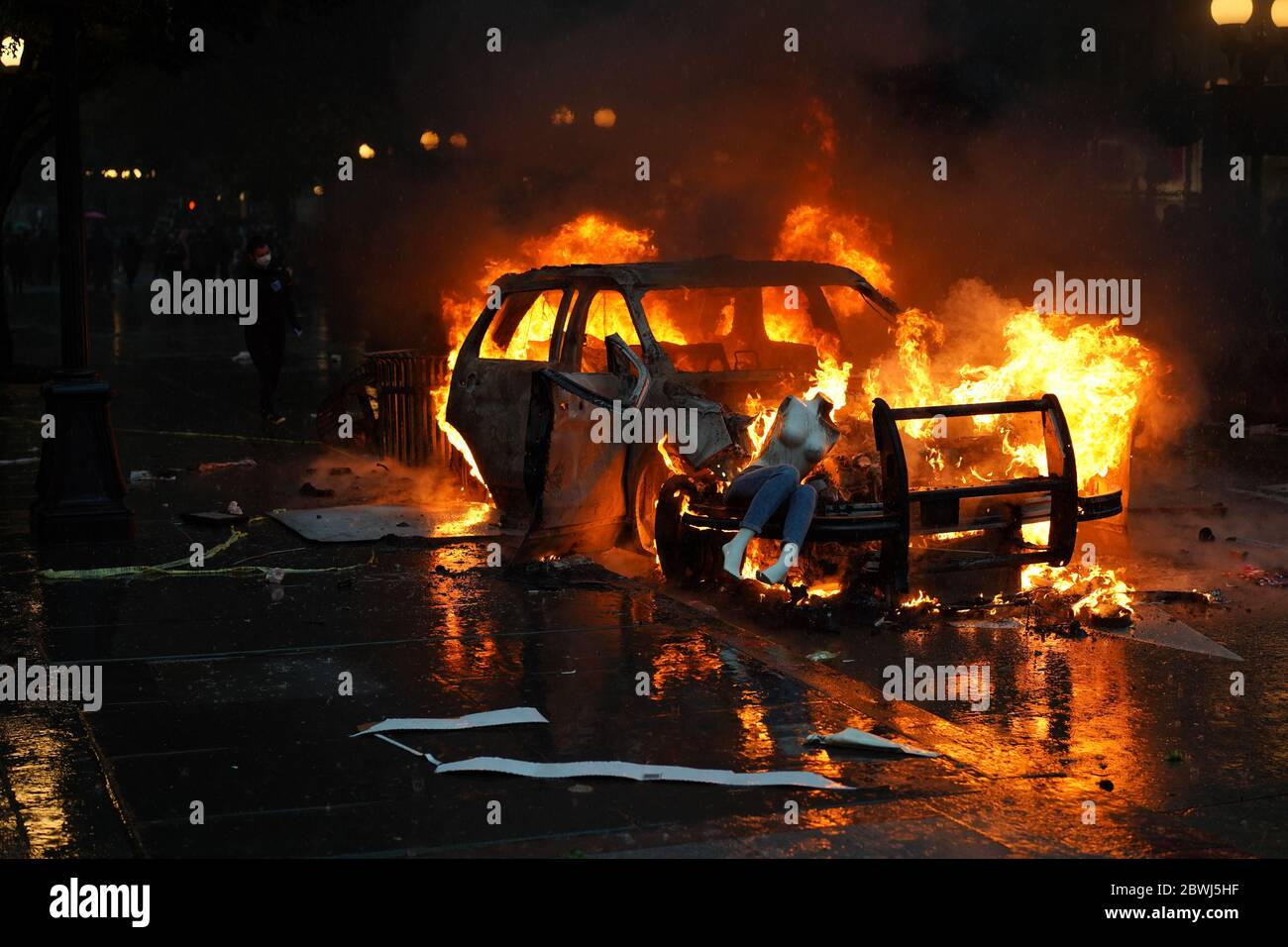 Un maniquí que fue saqueado de una tienda de ropa cercana se sienta encima de un coche de policía que fue incendiado durante las protestas de George Floyd en Seattle Foto de stock