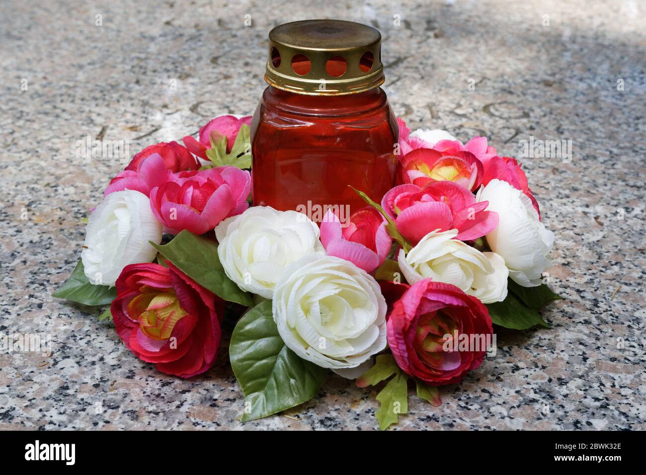 una vela grave y un arreglo de rosas en una lápida Foto de stock