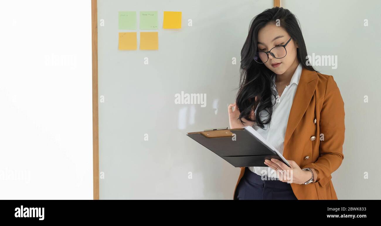 Joven empresaria asiática de negocios mirando el informe financiero en la oficina Foto de stock