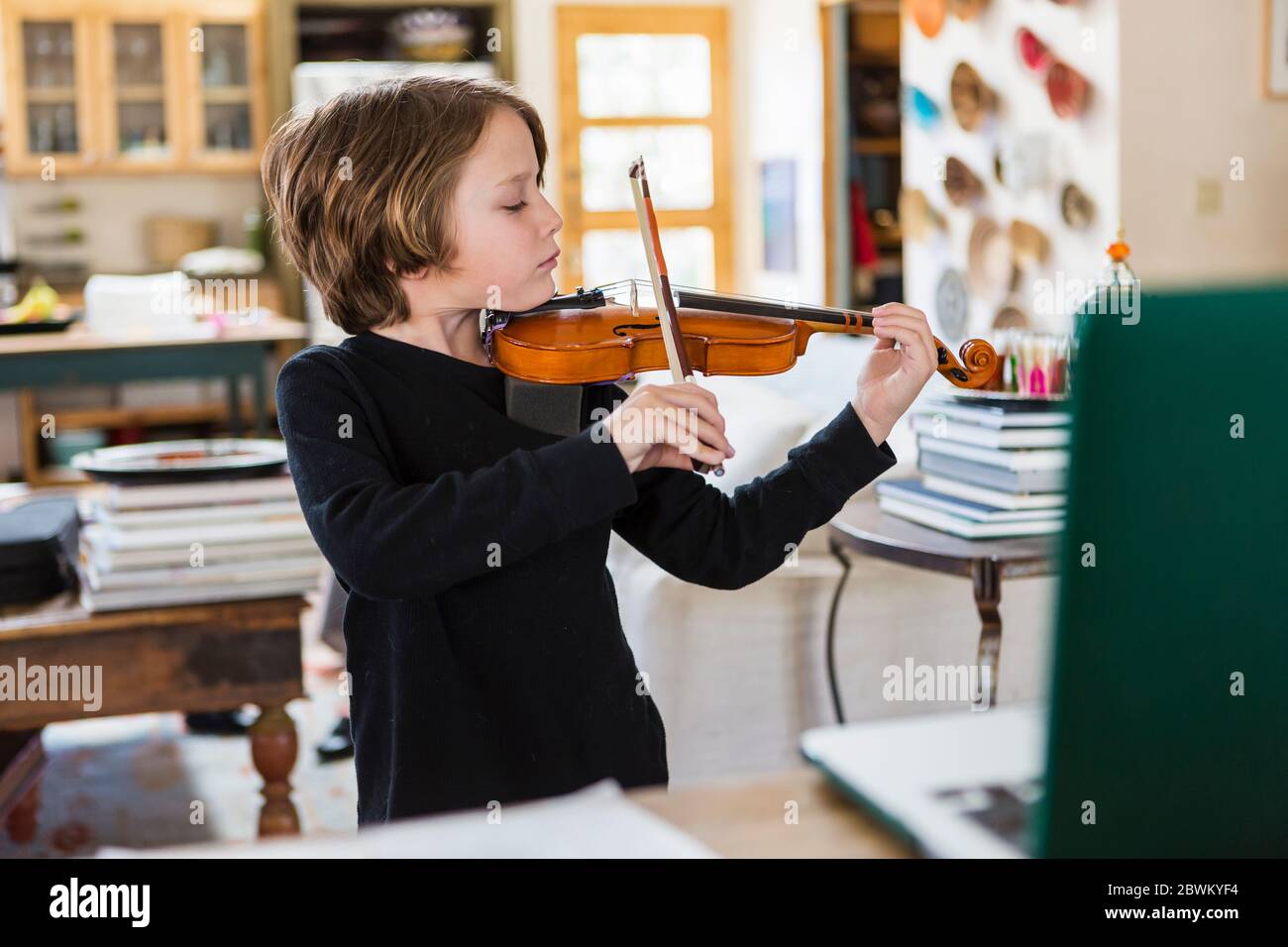 Niño de seis años tocando violín, teniendo una lección de video remota en  casa cerrada Fotografía de stock - Alamy