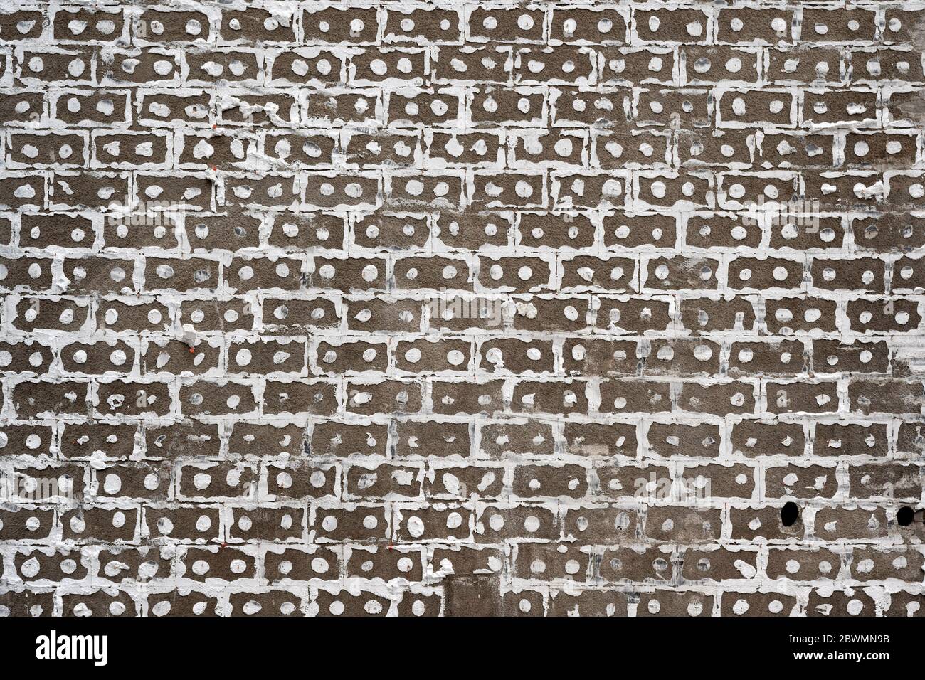 Los residuos adhesivos de los paneles de aislamiento en la fachada de una casa forman un patrón de rejilla en un sitio de demolición. Foto de stock