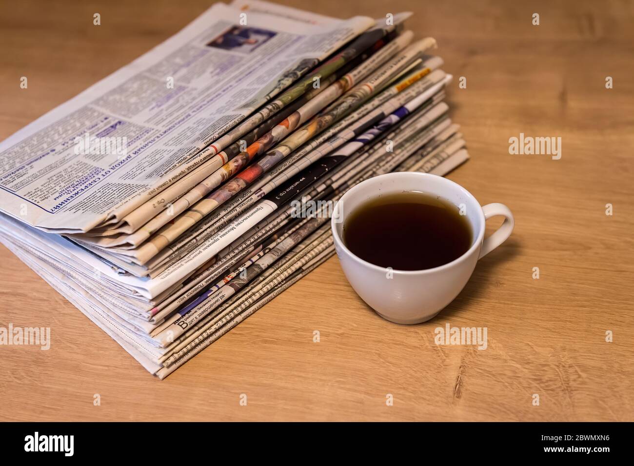 enfoque selectivo de la taza de té apilando periódicos doblados colocar sobre mesa de madera Foto de stock