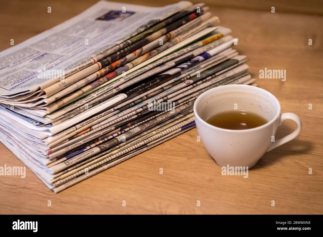 enfoque selectivo de la taza de té borracho apilar periódicos lugar plegado sobre mesa de madera Foto de stock