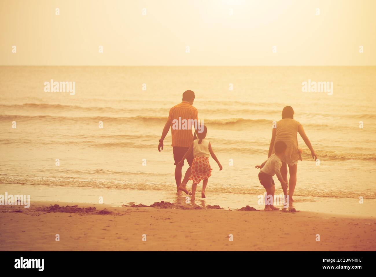 Vacaciones familiares puesta de sol feliz juntos en la playa amor con vivir fuerte lucha contra el virus con inmunidad social. Foto de stock