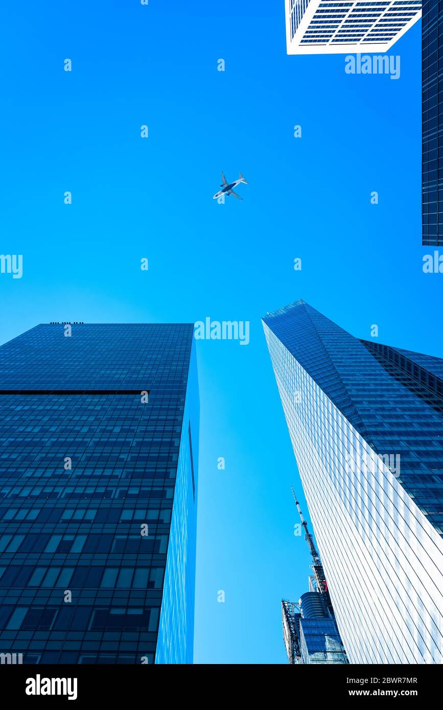 Nueva York, EE.UU. - 20 de junio de 2018: Vista de ángulo bajo de edificios de oficinas modernos y aviones contra el cielo en el centro de Manhattan. Foto de stock