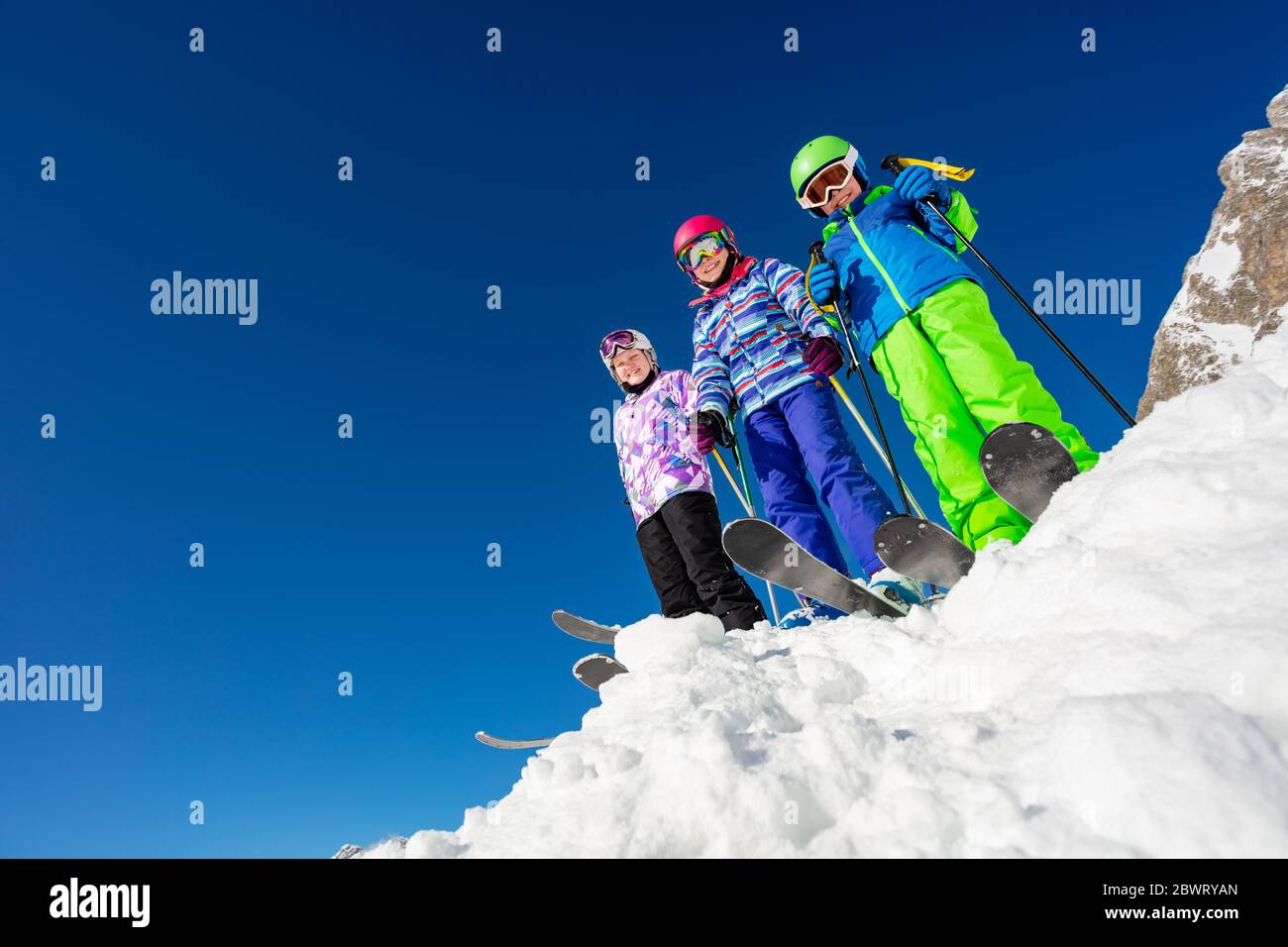 Los niños en la nieve vistiendo trajes de esquí, cascos y gafas Fotografía  de stock - Alamy