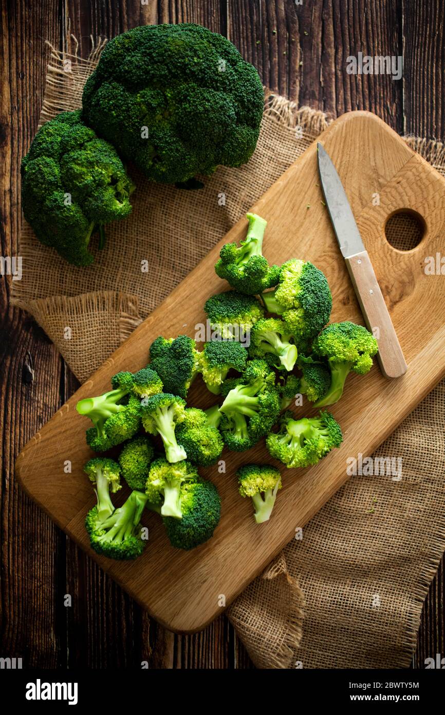 Coloque la alfombrilla, la tabla de cortar, el cuchillo de cocina y el brócoli fresco Foto de stock