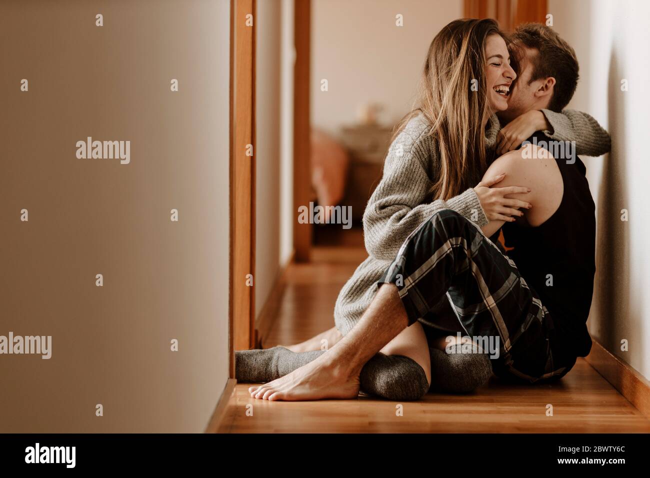 Feliz pareja joven sentada en el piso en casa Foto de stock