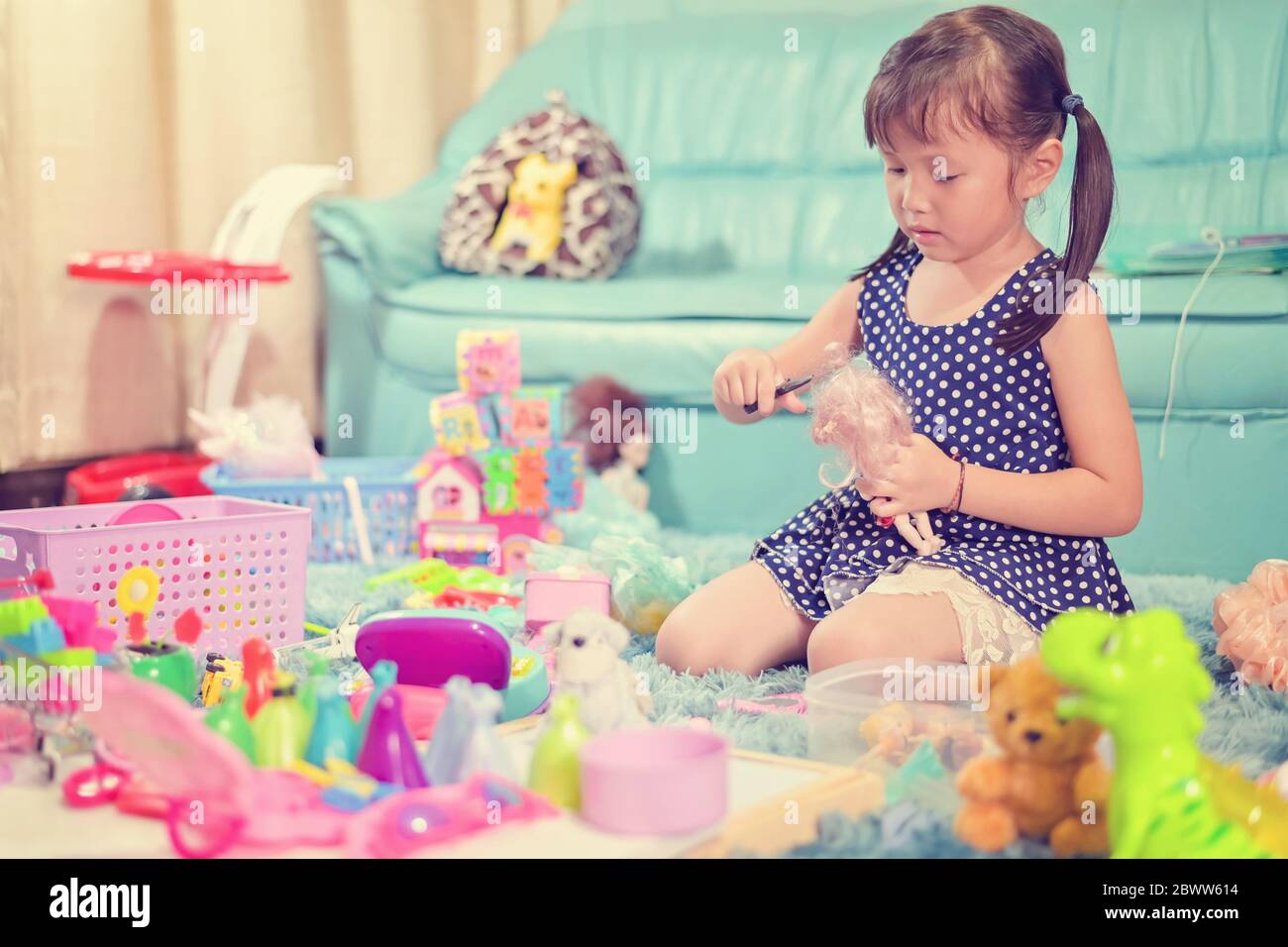Niño niña niña jugar juguetes desorden desordenado en la sala de estar un estado sucio o desordenado de juguete y muñeca en casa Foto de stock