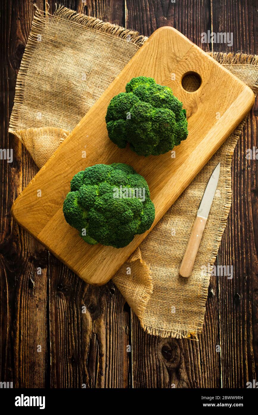 Coloque la alfombrilla, la tabla de cortar, el cuchillo de cocina y el brócoli fresco Foto de stock