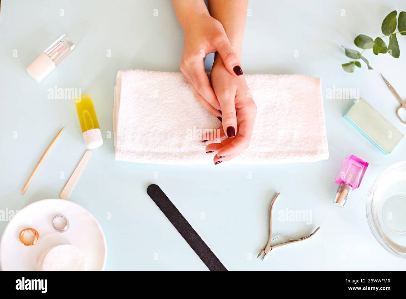 Vista superior de la cosecha mujer anónima con manicura oscura sentado en la mesa con varias herramientas durante el procedimiento de manicura profesional en el salón de spa Foto de stock